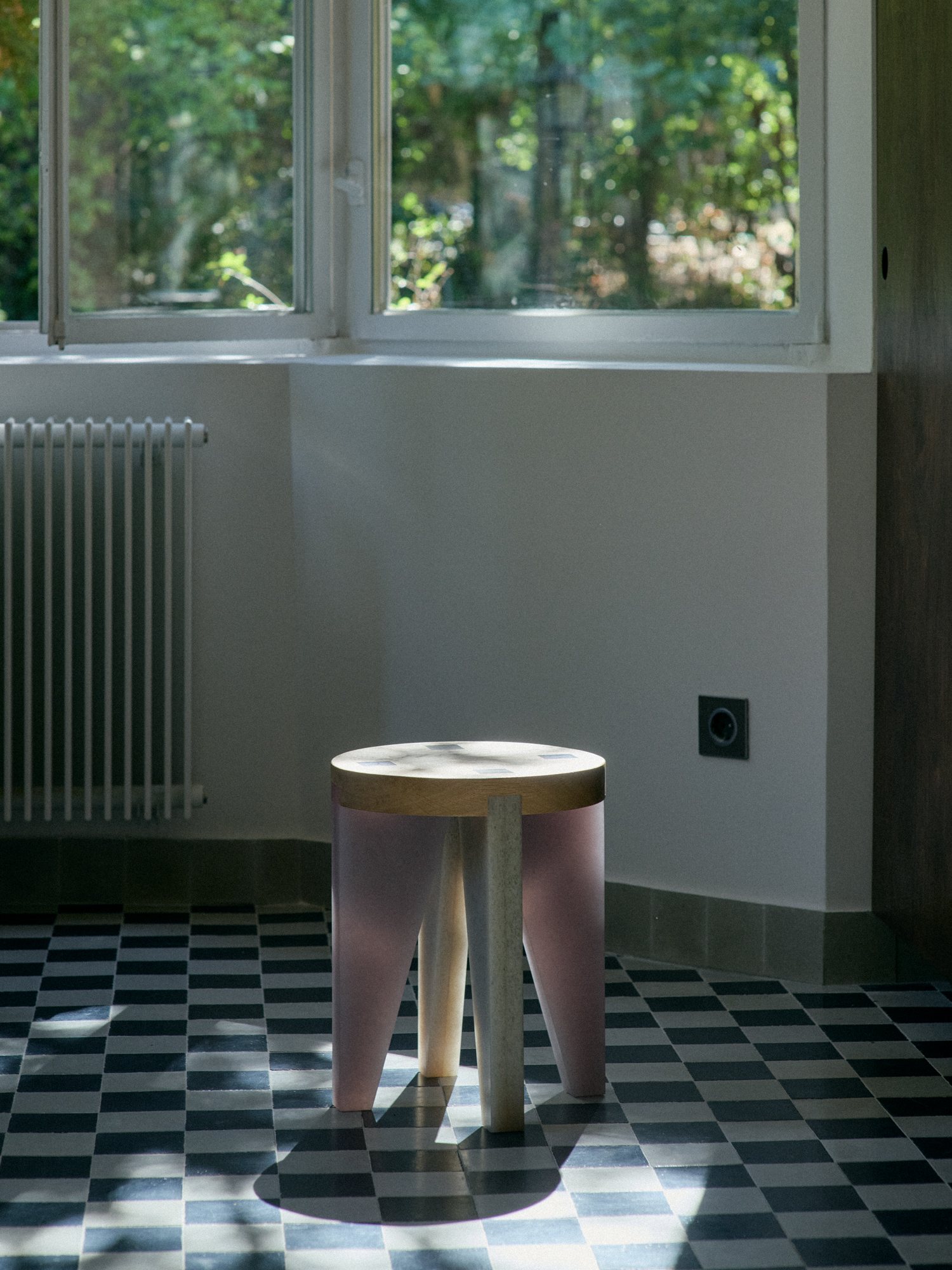 NANO Stool with pink legs on a checkerboard floor by the window